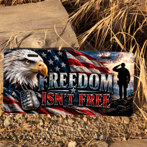 Freedom Isn’t Free patriotic license plate displayed outdoors beside rustic wood