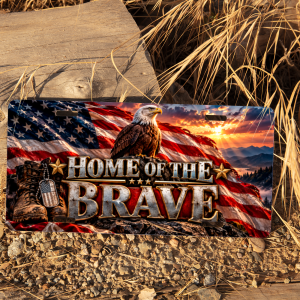 Home of the Brave patriotic eagle license plate displayed outdoors beside rustic wood